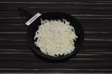 Шаг 2. Половину сыра выложить в чугунную сковороду, добавить сахар. Обжарить