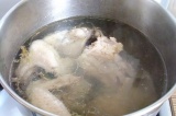 Шаг 3. Положить курицу, лук и чеснок в большую кастрюлю. Залить водой и кипятить