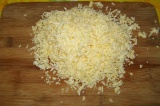 Шаг 4. Натереть сыр на крупной терке и выложить на грибы.