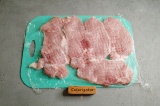 Шаг 1. Свинину нарезать на порционные куски и отбить через пищевую пленку.