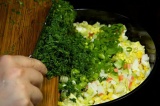 Шаг 6. Добавить яйца, огурец, зелень и крабовые палочки к салату в миску.