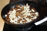 Шаг 6. В сковороду налить масло и высыпать лук с грибами. Жарить до готовности.