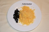 Шаг 3. Сыр натереть на терке, маслины порезать кружочками.