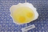 Шаг 1. Налить воду в тарелку, разбить два яйца, перемешать.
