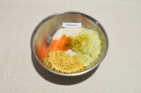 Шаг 4. В глубокую посуду выложить нут, капусту и морковь. Приправить специями