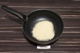 Шаг 4. В масло всыпать рис и обжарить в течение минуты, слегка помешивая.